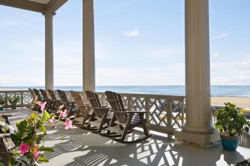 a porch with chairs and the ocean in the background at Harrison Hall Hotel in Ocean City