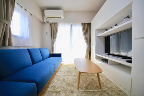 a living room with a blue couch and a tv at NorthRiverSKY in Tokyo