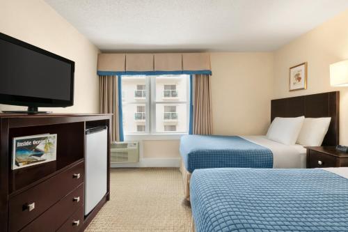 a hotel room with two beds and a flat screen tv at Harrison Hall Hotel in Ocean City