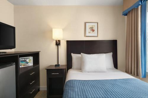 a hotel room with a bed and a flat screen tv at Harrison Hall Hotel in Ocean City