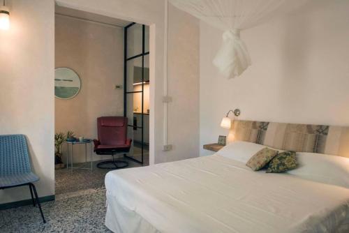 a bedroom with a white bed and a red chair at CASA DI ROBY - VENICE AIRPORT in Tessera