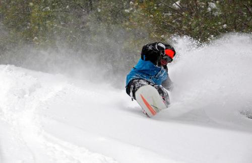 a man riding a snowboard down a snow covered slope at Massanutten's Regal Vistas by TripForth in McGaheysville