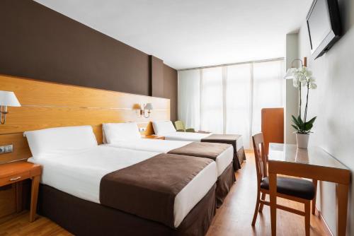 a hotel room with two beds and a desk at Exe Las Palmas in Las Palmas de Gran Canaria