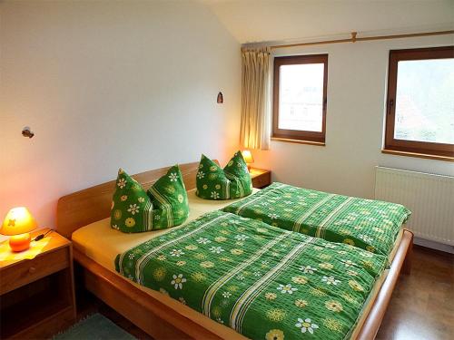 Schlafzimmer mit einem Bett mit grüner Bettwäsche und Kissen in der Unterkunft Gästehaus Schrot in Bad Schandau