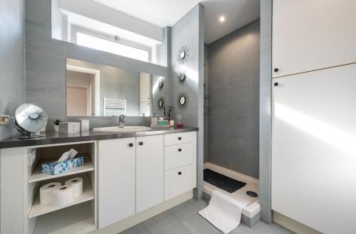 une salle de bain blanche avec un lavabo et un miroir dans l'établissement Paris Champs-Elysées/Neuilly 2 pièces avec terrasse, à Neuilly-sur-Seine