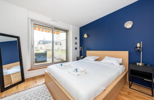 une chambre avec un grand lit avec un mur bleu dans l'établissement Paris Champs-Elysées/Neuilly 2 pièces avec terrasse, à Neuilly-sur-Seine