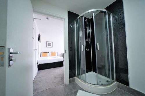 a glass shower in a bathroom with a bedroom at TBH Hotel in Barking