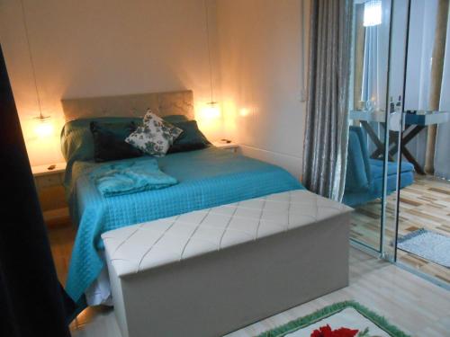 1 dormitorio con 1 cama con sábanas azules y espejo en Pousada Jolie Maison, en São Francisco do Sul