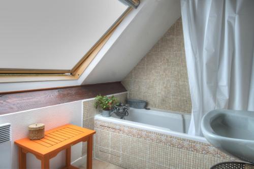 
a bath tub sitting next to a window in a bathroom at Cottage Prairie Bonheur in Magny-les-Hameaux
