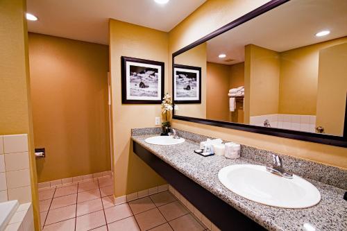 a bathroom with two sinks and a large mirror at Heritage Inn in Great Falls