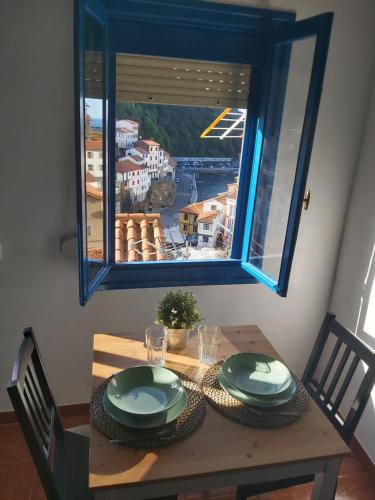 a wooden table with a view of a city from a window at Casa de pescadores con vistas al mar in Cudillero