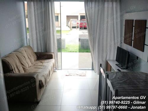 sala de estar con sofá y puerta corredera de cristal en Apartamentos GV, en Xangri-lá
