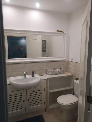 a bathroom with a sink and a toilet and a mirror at Waves Alvor in Portimão