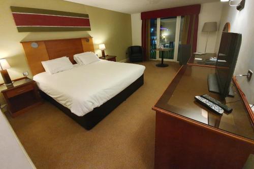 a hotel room with a bed and a desk with a computer at Towers Hotel & Spa in Swansea