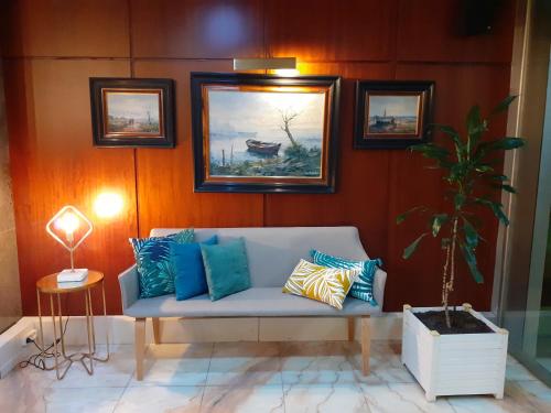 a living room with a couch and paintings on the wall at Hotel Marqués de Santillana in Torrelavega