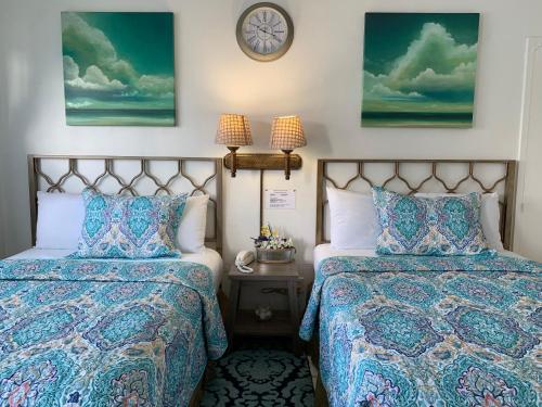 a bedroom with two beds and a clock on the wall at International Inn on the Bay in Miami Beach