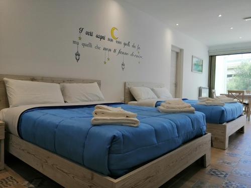 2 letti in una camera da letto con coperte blu di Sicily Rooms Appartamenti a Carini