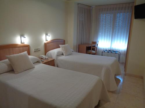 a hotel room with two beds and a window at Hostal El Retiro in Almoradí