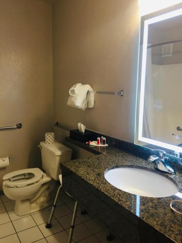 a bathroom with a toilet and a sink and a mirror at Super 8 by Wyndham Swift Current in Swift Current