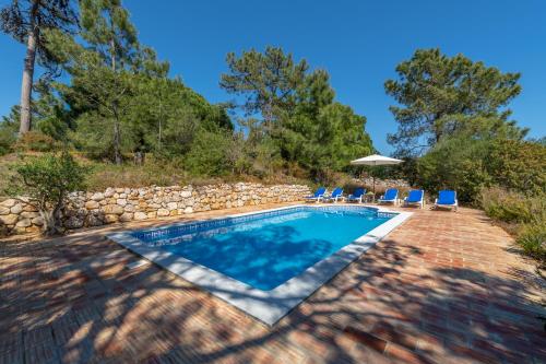 a swimming pool in a yard with chairs and an umbrella at Charming Seaside Cottage Casa Rosa - Somewhere Special in Luz de Tavira
