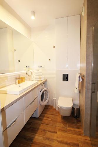 a bathroom with a toilet sink and a washing machine at Aqua Apartments Sunset in Reda