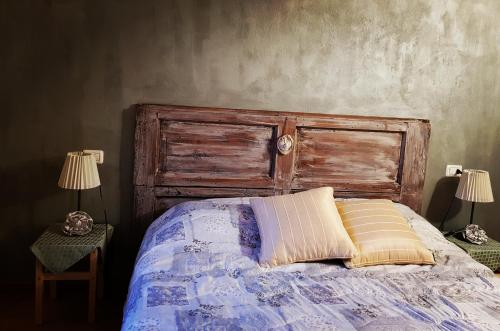 a bed with a wooden head board and two lamps at La Cappuccina in Corniglio