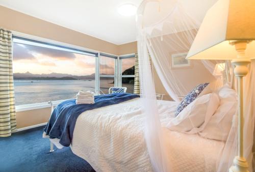 a bedroom with a bed with a view of the ocean at Coromandel Apartments in Coromandel Town