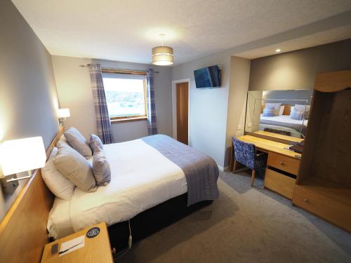 een hotelkamer met een groot bed en een bureau bij Park Hotel in Thurso