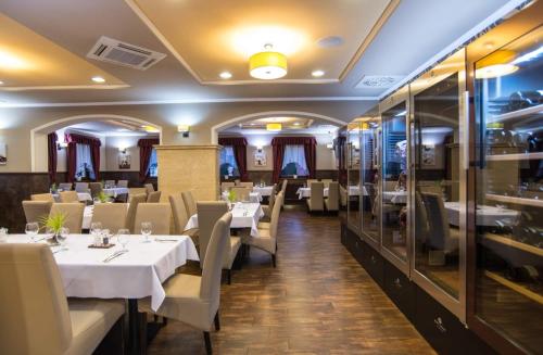 a dining room with white tables and chairs at Corvin Pension and Restaurant in Veľký Meder