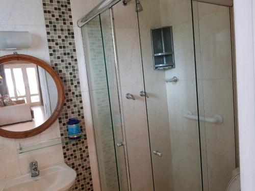 a bathroom with a shower and a sink and a mirror at Escolha flat família com cozinha ou suítes separadas e independentes in Conservatória
