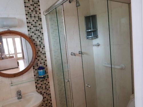 a bathroom with a shower and a sink and a mirror at Flat e suítes com deque, cozinha e churrasqueira in Conservatória