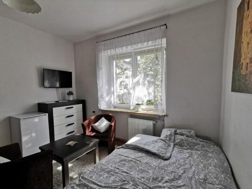 a bedroom with a bed and a chair and a window at Krakow Centrum Gurgacza Apartments in Krakow