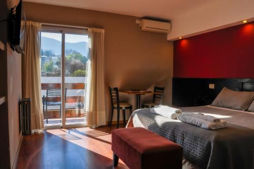 Un dormitorio con una cama y un balcón con una mesa. en Aguas Claras Hosteria, en Santa Rosa de Calamuchita