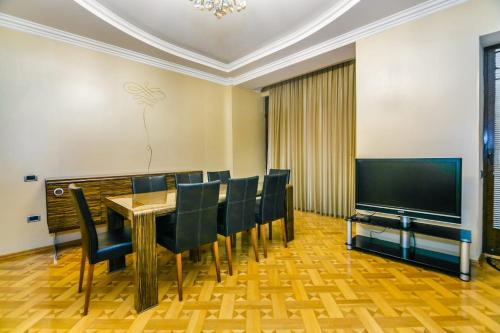 een eetkamer met een tafel en stoelen en een televisie bij VİP Apartment number one in Baku