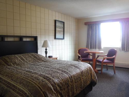 a hotel room with a bed and a table and chairs at Haida Way Motor Inn in Port McNeill