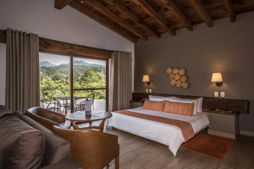 a bedroom with a bed and a couch and a window at Hotel Avandaro Golf & Spa Resort in Valle de Bravo