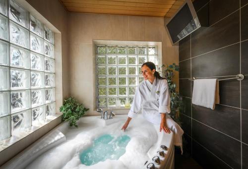 une femme debout dans une baignoire dans une salle de bains dans l'établissement Vuokatin Aateli Castle, à Vuokatti