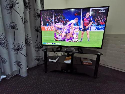 a flat screen tv with a football game on it at Capri on Fenton in Rotorua