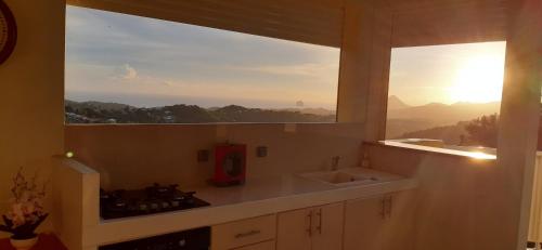 a kitchen with a sink and a window with the sunset at Villa Lineddy in Quartier la Fleury Guiné