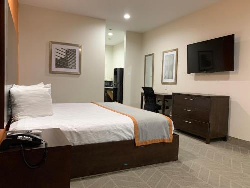a bedroom with a bed and a desk and a television at Scottish Inn & Suites - IAH Airport in Humble