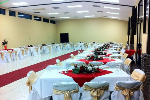 une grande salle de banquet avec des tables et des chaises blanches dans l'établissement Best Western El Sitio Hotel, à Liberia