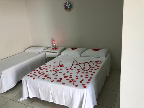 a room with two beds with red roses on a table at Pousada Xero in Capitólio