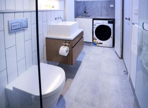 a bathroom with a toilet sink and a washing machine at Flagstaff Green Apartments in Melbourne
