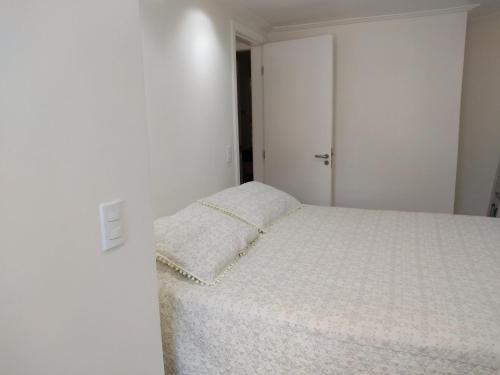 ein Schlafzimmer mit einem weißen Bett und einem Kissen darauf in der Unterkunft Mamelucos Chalé 11 Praia do Flamengo in Salvador