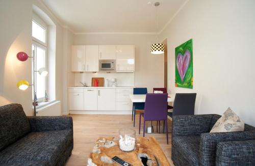 a living room with a couch and a table and a kitchen at Apartment Eisberg 2 mit Balkon in Norderney