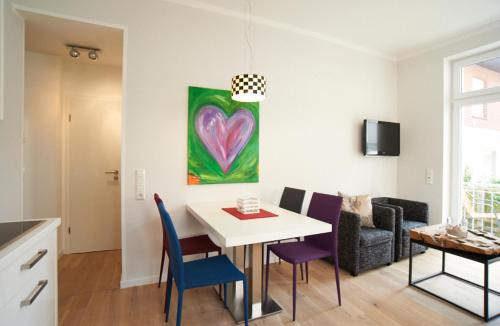 - un salon avec une table, des chaises et un tableau dans l'établissement Apartment Eisberg 2 mit Balkon, à Norderney