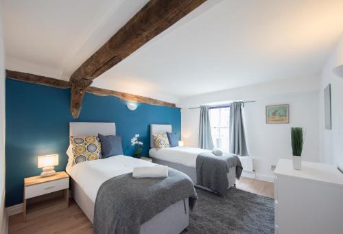 Colchester Town Duplex Apartment في كولشستر: سريرين في غرفة بجدران زرقاء