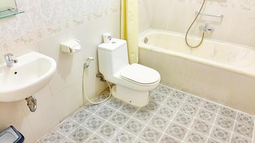 a bathroom with a toilet and a sink and a tub at Masainn Hotel Kuta in Kuta