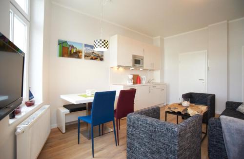 ein Wohnzimmer mit einem Tisch und Stühlen sowie eine Küche in der Unterkunft Apartment Eisberg 3 mit schöner Balkonterrasse in Norderney
