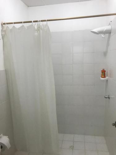 a bathroom with a shower with a white shower curtain at Casa Blue Tortuga in Ballenita